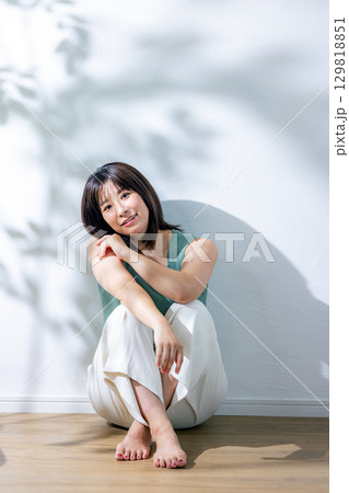 夏の日差し　壁にもたれる女性 129818851