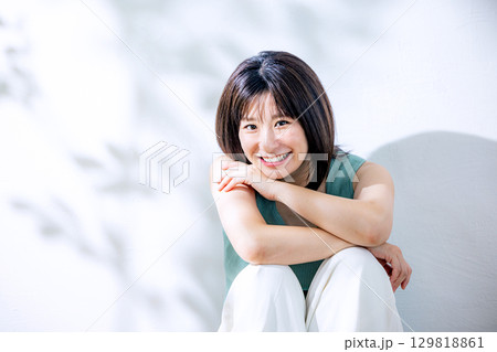 夏の日差し　壁にもたれる女性 129818861