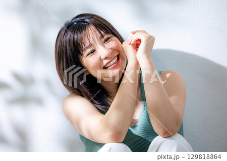 夏の日差し　壁にもたれる女性 129818864