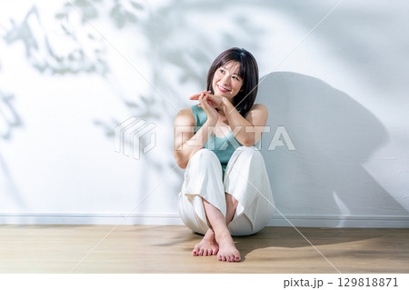 夏の日差し　壁にもたれる女性 129818871