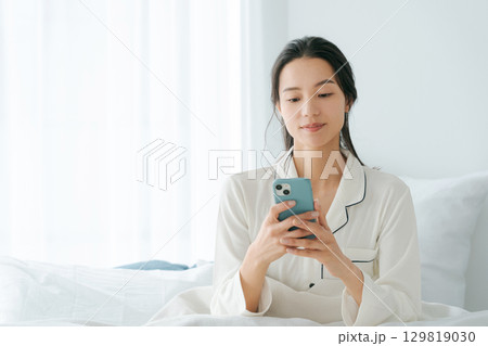 ベッドでスマホを操作する女性 129819030