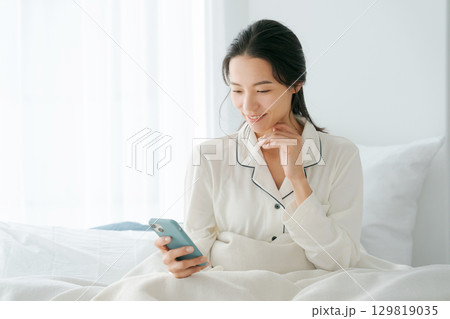 ベッドでスマホを操作する女性 129819035