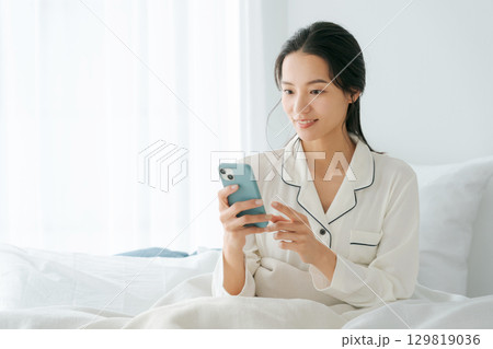 ベッドでスマホを操作する女性 ベッドでスマホを操作する女性 129819036