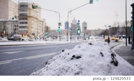 Snow pile by the roadside covering dirty frozen ground in Moscow winter 129820533