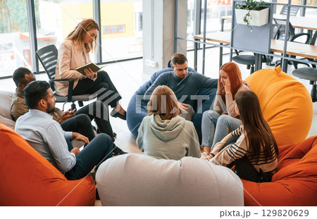 Redhead woman is feeling bad. Group of people are having therapy meeting together Redhead woman is feeling bad. Group of people are having therapy meeting together 129820629