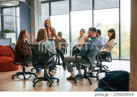 Against panoramic windows. Group of people are having therapy meeting together Against panoramic windows. Group of people are having therapy meeting together 129820654