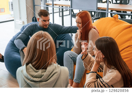 Redhead woman is feeling bad. Group of people are having therapy meeting together 129820856