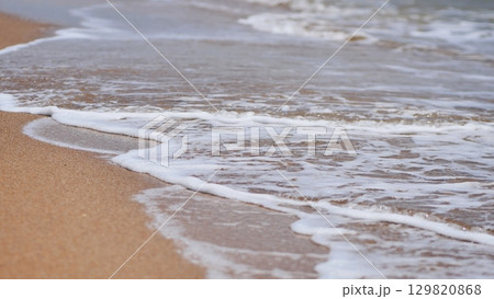 Gentle white sea foam caressing sandy shoreline in crimea, epitomizing tranquil coastal serenity 129820868
