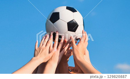 School friends holding soccer ball celebrating a victory under a blue sky, concept of teamwork and success School friends holding soccer ball celebrating a victory under a blue sky, concept of teamwork and success 129820887