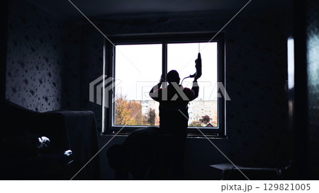 Silhouettes of builders drill the walls to install windows. Silhouettes of builders drill the walls to install windows. 129821005