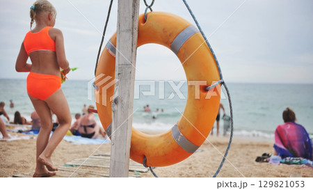 Orange lifebuoy hanging on wooden pole on Koktebel beach in Crimea 129821053