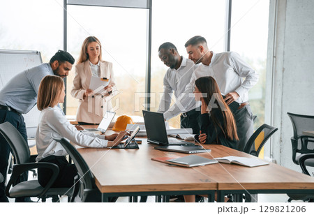 On the meeting, discussing the plans. Group of office workers are together indoors 129821206