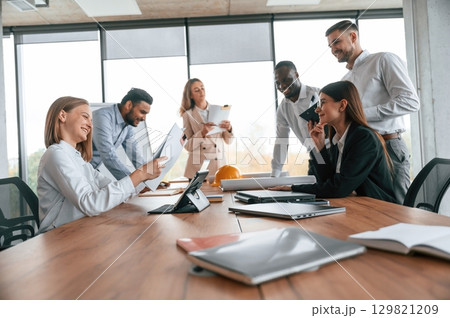On the meeting, discussing the plans. Group of office workers are together indoors 129821209
