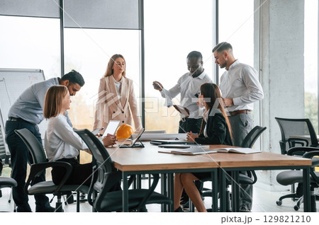 Against the panoramic window, having a meeting. Group of office workers are together indoors Against the panoramic window, having a meeting. Group of office workers are together indoors 129821210