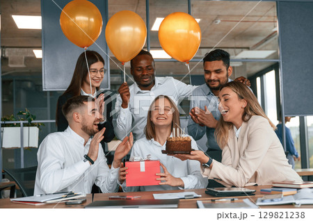 Cake with candles. Employee having a birthday in the office, group of workers 129821238