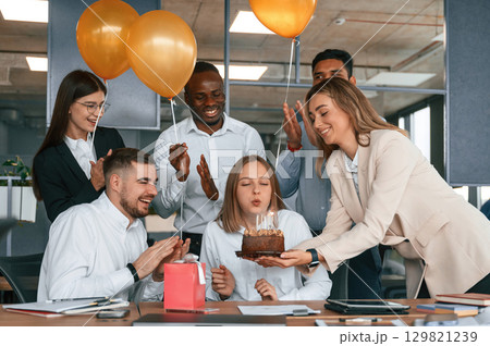 Cake with candles. Employee having a birthday in the office, group of workers 129821239