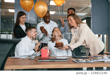 Cake with candles. Employee having a birthday in the office, group of workers 129821240