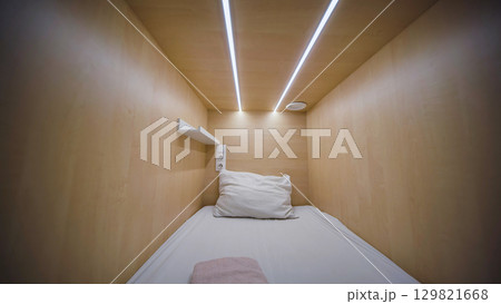 Modern capsule hotel room interior showing comfortable bed, pillow and led lights 129821668