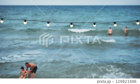 Father and son playing on the beach with string lights and swimmers in Crimea Father and son playing on the beach with string lights and swimmers in Crimea 129821886