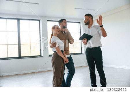 Brand new apartment. Realtor shows a room to a young couple Brand new apartment. Realtor shows a room to a young couple 129822451