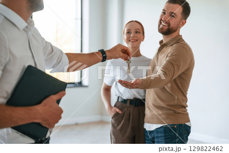 Giving the keys. Realtor shows an apartment to a young couple 129822462