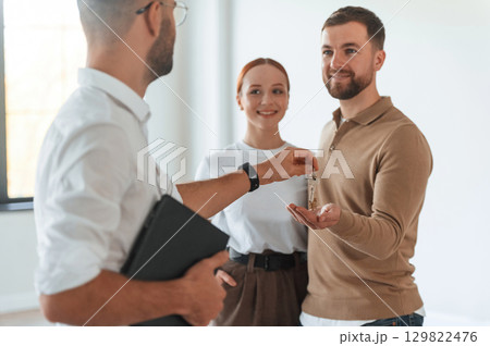 Customers bought the place, receiving the keys. Realtor shows an apartment to a young couple 129822476