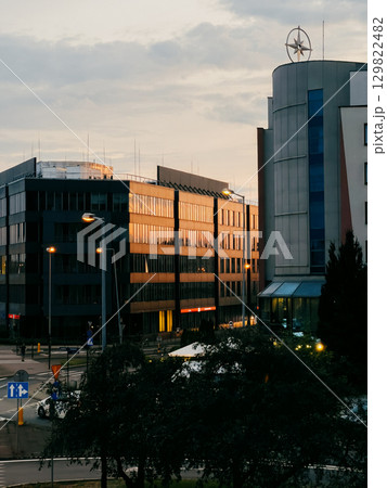 Glass facades of modern office buildings reflect warm golden light of setting sun, creating vibrant and dynamic urban scene at dusk. Sunlight casting golden reflections on glass skyscrapers Glass facades of modern office buildings reflect warm golden light of setting sun, creating vibrant and dynamic urban scene at dusk. Sunlight casting golden reflections on glass skyscrapers 129822482