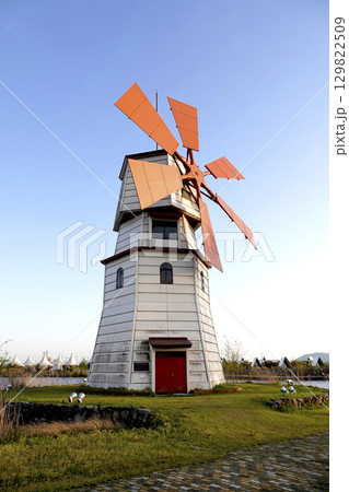 青空の下湖畔に建つ風車 129822509
