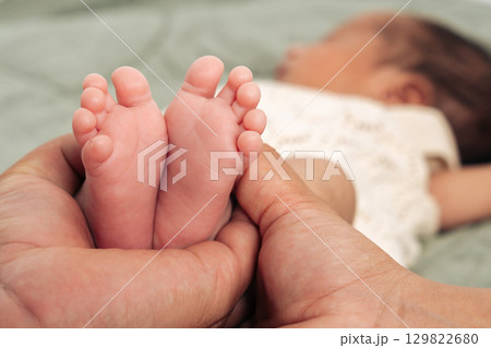 Tiny newborn feet are tenderly cradled in a parent's hands symbolizing love, care, and family bonding. This intimate moment captures the essence of parenthood and the miracle of new life Tiny newborn feet are tenderly cradled in a parent's hands symbolizing love, care, and family bonding. This intimate moment captures the essence of parenthood and the miracle of new life 129822680