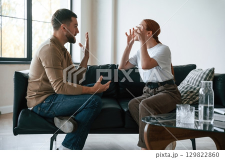 Side view of couple that are arguing. Sitting on sofa 129822860