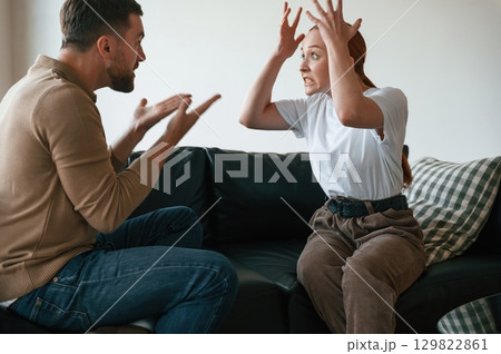 Side view of couple that are arguing. Sitting on sofa 129822861