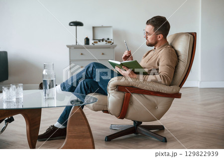 Male psychologist is sitting in the chair with notepad in the office 129822939