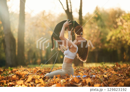 Holding animal in hands. Woman is with her cute dog in the autumn forest 129823192