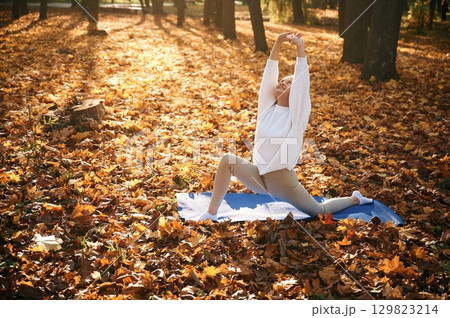 On the mat. Young beautiful woman is doing yoga in the autumn park On the mat. Young beautiful woman is doing yoga in the autumn park 129823214