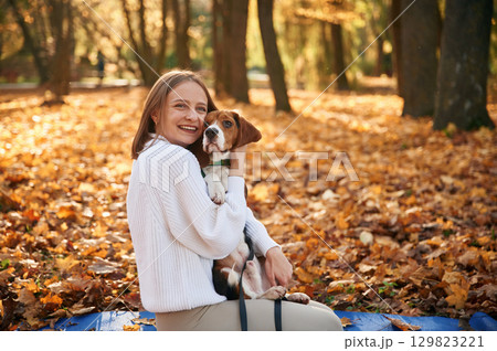 Embracing the animal. Woman is with her cute dog in the autumn forest Embracing the animal. Woman is with her cute dog in the autumn forest 129823221