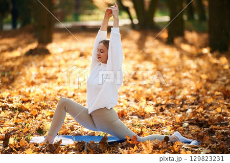 Young beautiful woman is doing yoga in the autumn park 129823231
