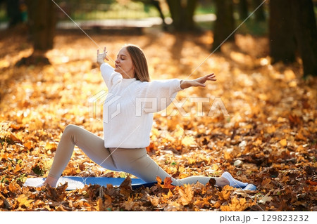 Young beautiful woman is doing yoga in the autumn park 129823232