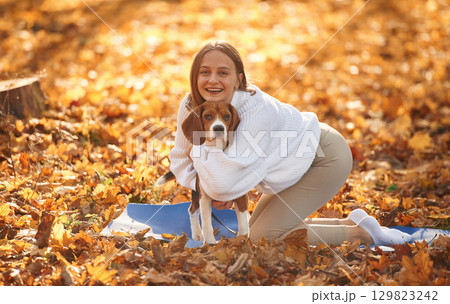 Embracing the animal. Woman is with her cute dog in the autumn forest 129823242