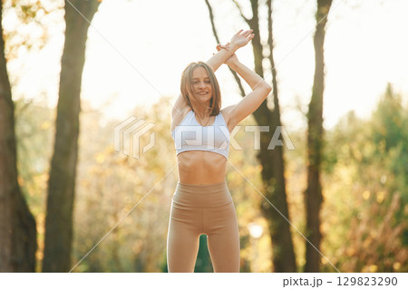 Illuminated by sunlight. Young beautiful woman is doing yoga in the autumn park Illuminated by sunlight. Young beautiful woman is doing yoga in the autumn park 129823290