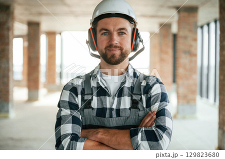 Portrait, in hard hat. Construction worker in uniform in empty unfinished room 129823680