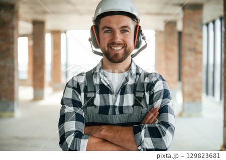 Portrait, in hard hat. Construction worker in uniform in empty unfinished room 129823681