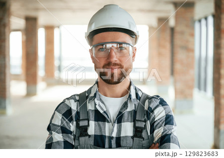 Portrait, in hard hat. Construction worker in uniform in empty unfinished room 129823683