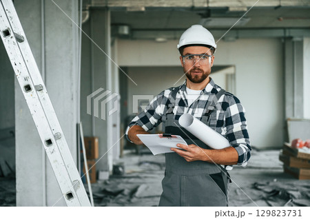 Manager is with plan in hands. Repairman in uniform is in the unfinished building Manager is with plan in hands. Repairman in uniform is in the unfinished building 129823731