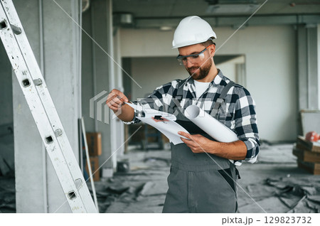 Manager is with plan in hands. Repairman in uniform is in the unfinished building 129823732