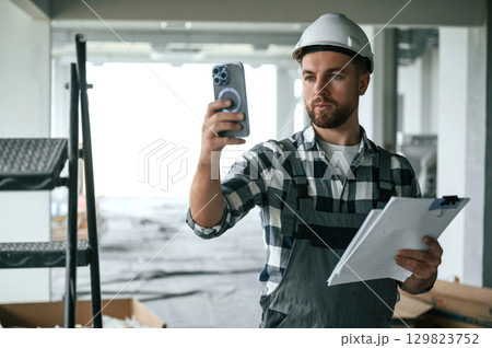 Construction worker in uniform in empty unfinished room 129823752