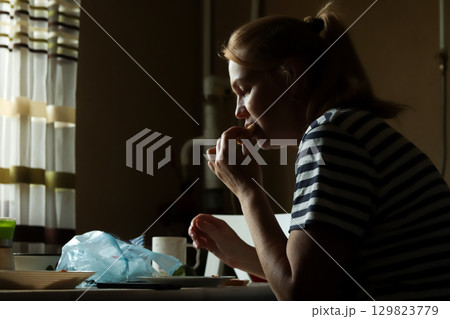 silhouette of a woman eating a sweet snack late at night. a woman eating a midnight meal. night lifestyle food silhouette 129823779