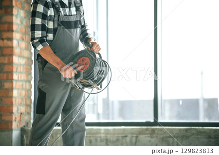 Close up view of repairman indoors in unfinished building Close up view of repairman indoors in unfinished building 129823813