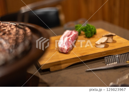 Raw pork belly and mushrooms on a wooden cutting board with parsley garnish, ingredients for barbecue Raw pork belly and mushrooms on a wooden cutting board with parsley garnish, ingredients for barbecue 129823967