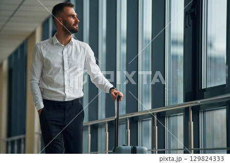 Standing, looking through the windows. Young handsome man in the airport 129824333