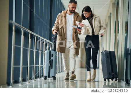Front view, walking. Couple are in the airport hall together 129824559